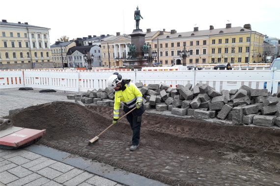 Tutkija Heli Lehto harjaa esiin mukulakiveystä Hallituskadun varrella syksyllä 2021.